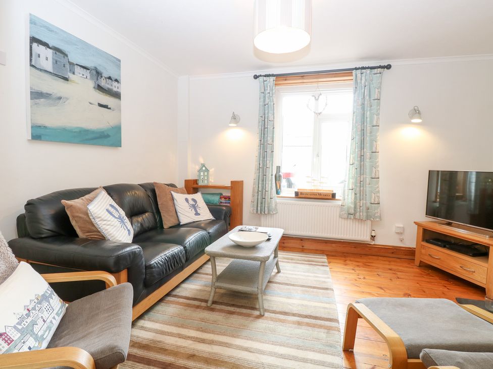 A living room with a sofa, coffee table, and television at Driftwood Cottage in Heacham