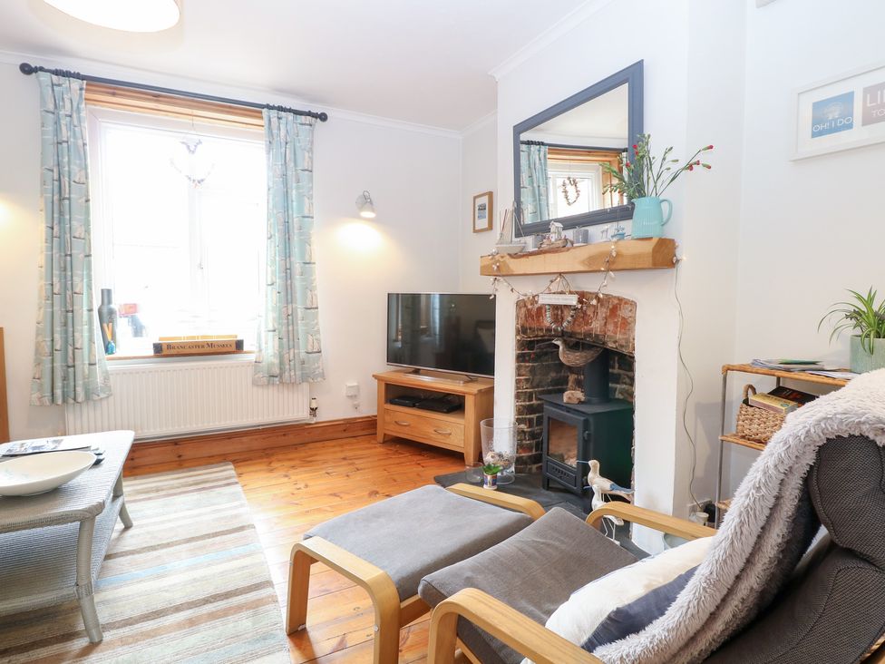 A living room with a television and fireplace at Driftwood Cottage Heacham