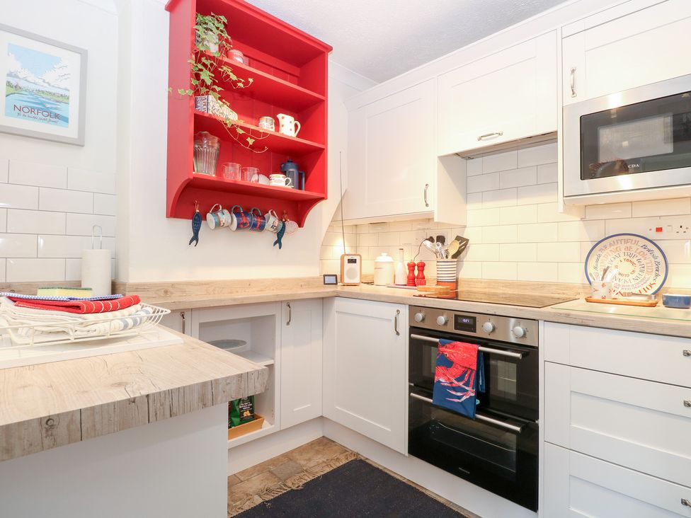 A kitchen with shelves and appliances at Driftwood Cottage in Heacham
