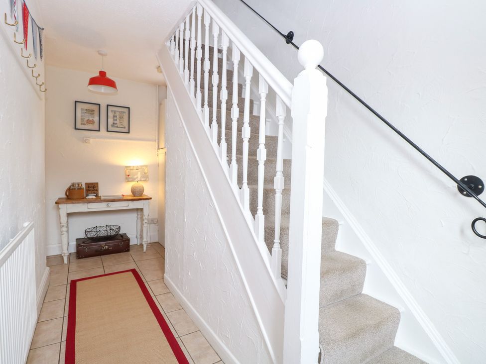 A hallway with a staircase and console table at Driftwood Cottage in Heacham