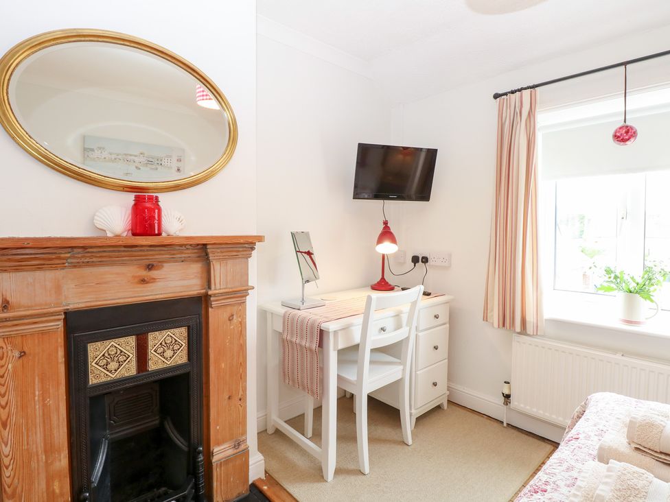 A bedroom with a fireplace, desk, and tv at Driftwood Cottage in Heacham