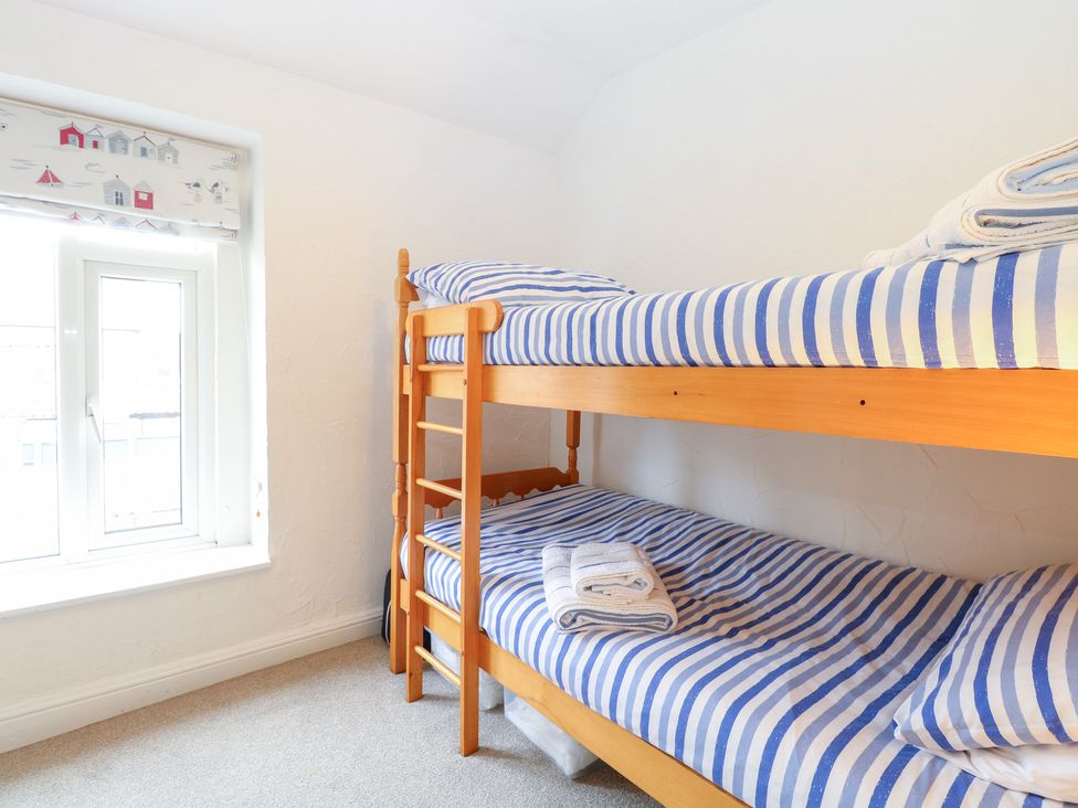 A bunk bed with striped sheets in a bedroom at Driftwood Cottage Heacham