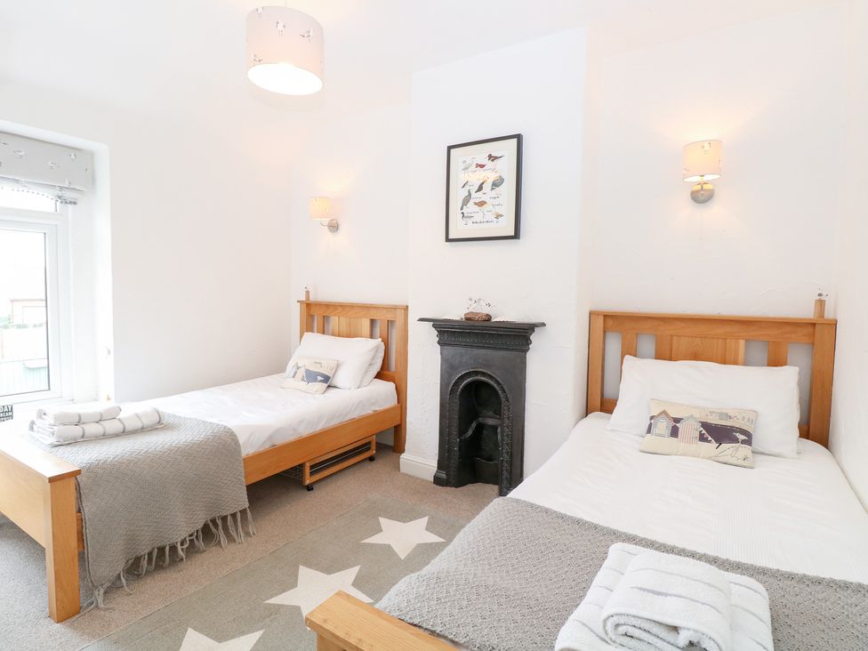A bedroom with two single beds and a fireplace at Driftwood Cottage Heacham