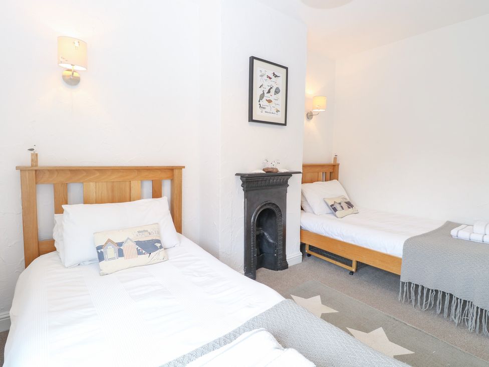 A bedroom with two beds and a fireplace at Driftwood Cottage in Heacham