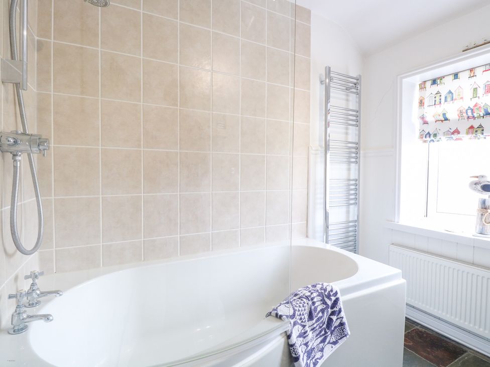 A bathroom with a bathtub and a towel at Driftwood Cottage in Heacham