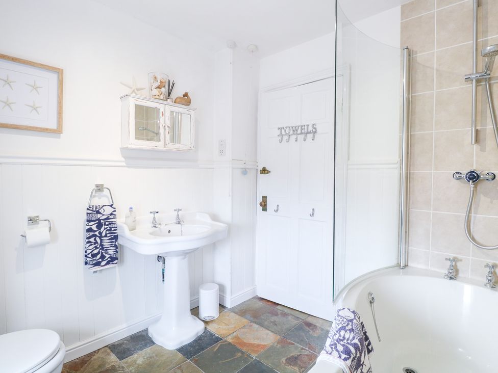 A bathroom with a sink, shower, and bathtub at Driftwood Cottage in Heacham