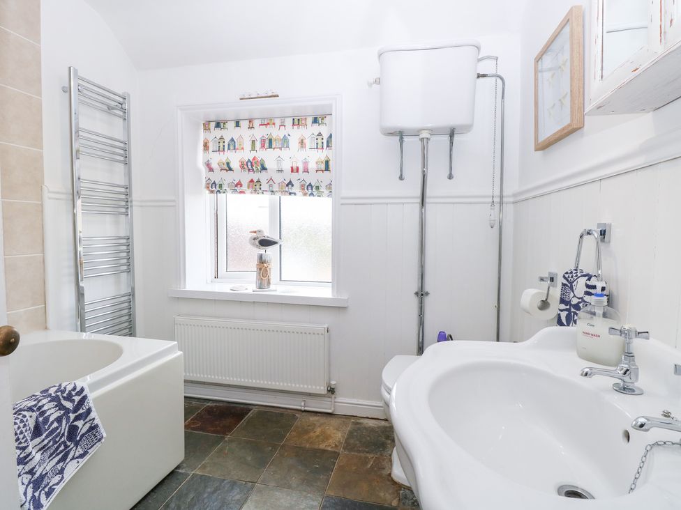 A bathroom with a bathtub, toilet, and sink at Driftwood Cottage in Heacham
