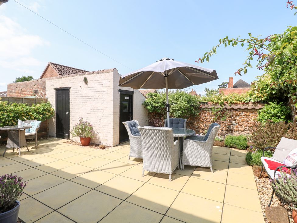 A garden with a patio set and shed at Driftwood Cottage in Heacham