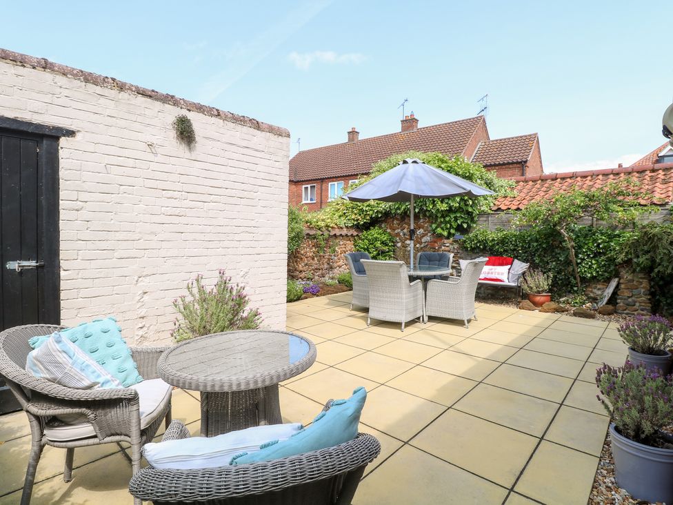 A garden with a table and chairs under an umbrella at Driftwood Cottage Heacham