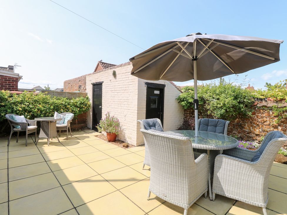 A garden with a table and chairs under an umbrella at Driftwood Cottage Heacham