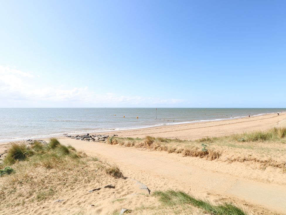 A beach scene with sand and calm sea at Driftwood Cottage in Heacham