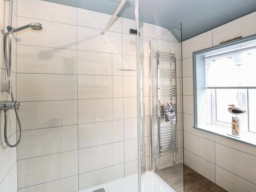 A bathroom with a shower and towel rail at Driftwood Cottage in Heacham