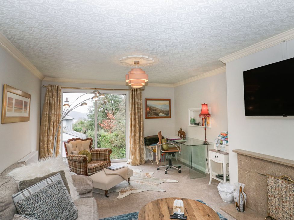 A living room with a sofa, armchair, and desk at Kempton in Bowness-on-Windermere
