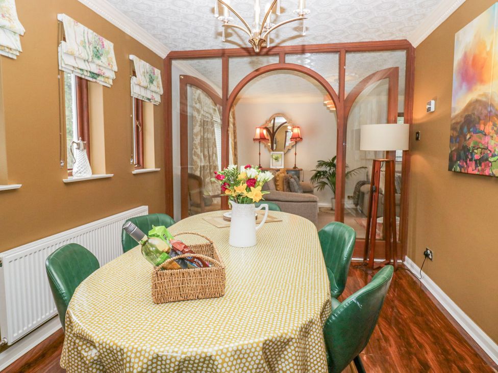 A dining room with a table and flowers at Kempton in Bowness-on-Windermere