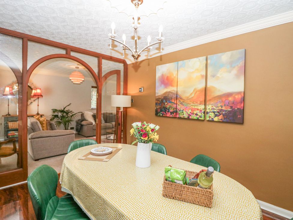 A dining room with a table and green chairs at Kempton in Bowness-on-Windermere