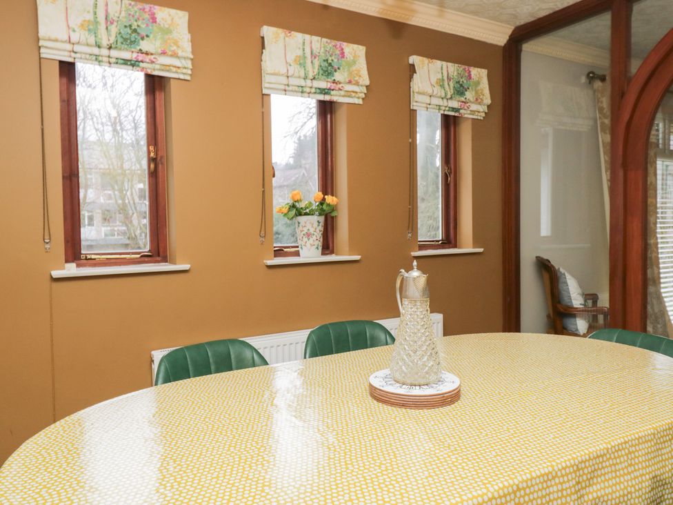 A dining room with a round table and windows at Kempton in Bowness-on-Windermere
