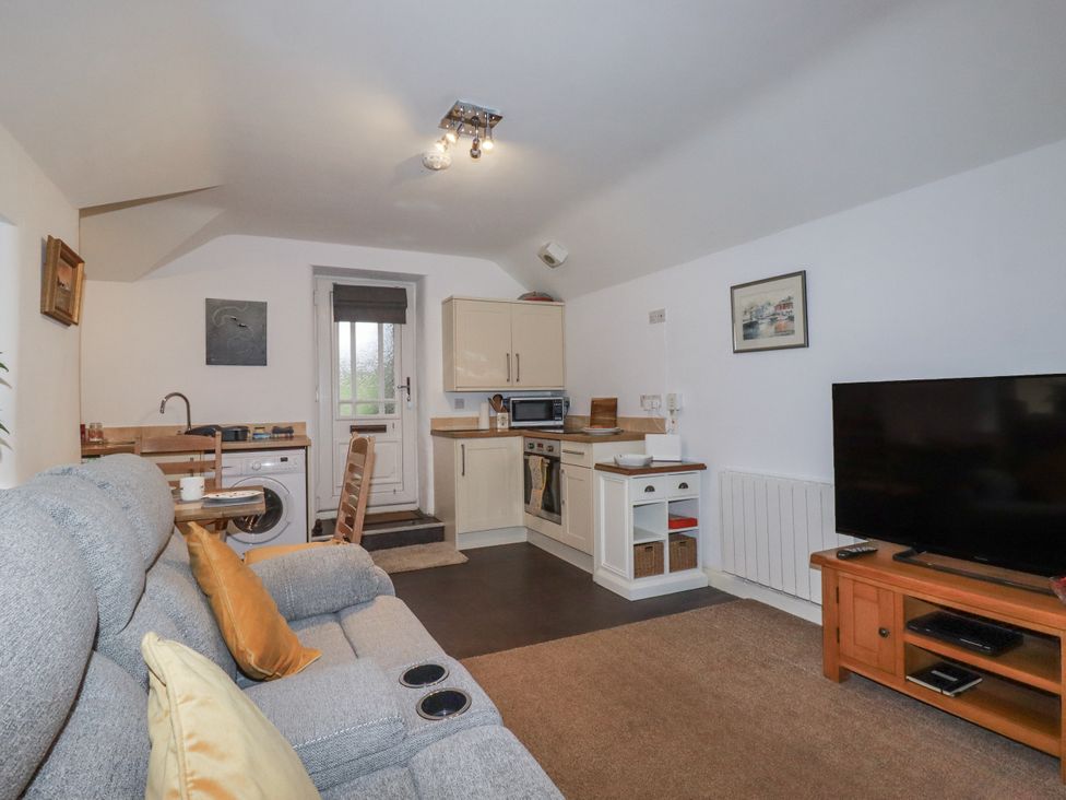 A living room with a sofa and kitchen area at Bramble Barn Inches near Lanivet