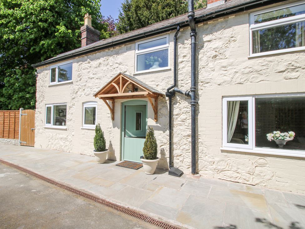 Exterior view of a stone house with a green door and two potted plants at Pennal Cottage in Maesbury Marsh near Knockin