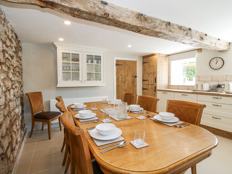 A dining room with a wooden table and chairs set with plates and bowls at Pennal Cottage Maesbury Marsh near Knockin