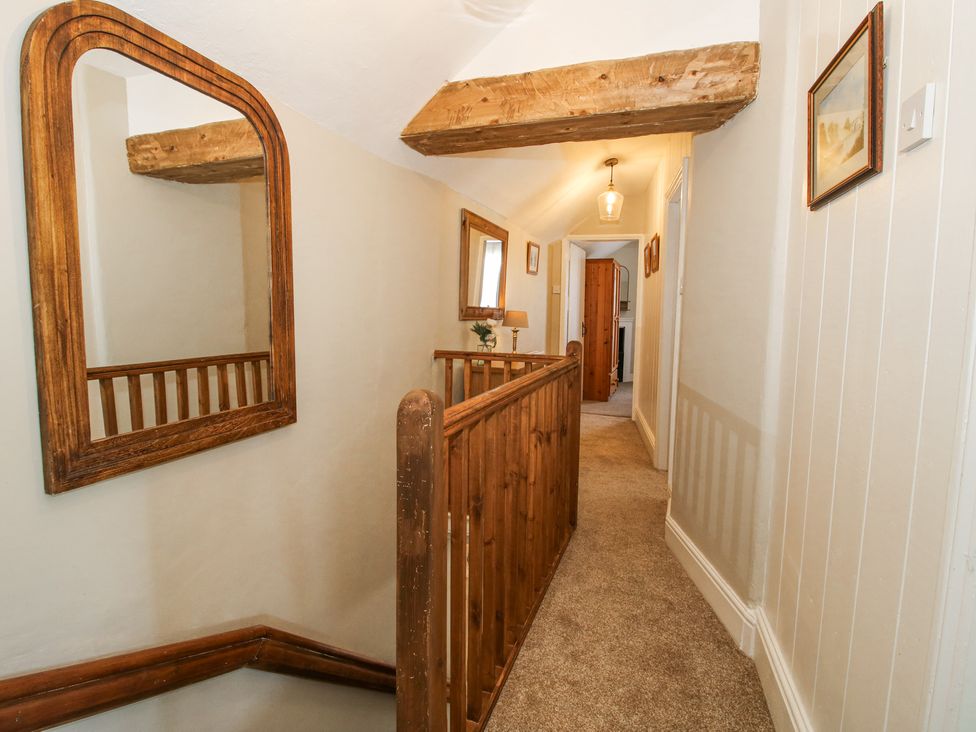 A carpeted hallway with wooden railing a mirror and wall art at Pennal Cottage Maesbury Marsh near Knockin