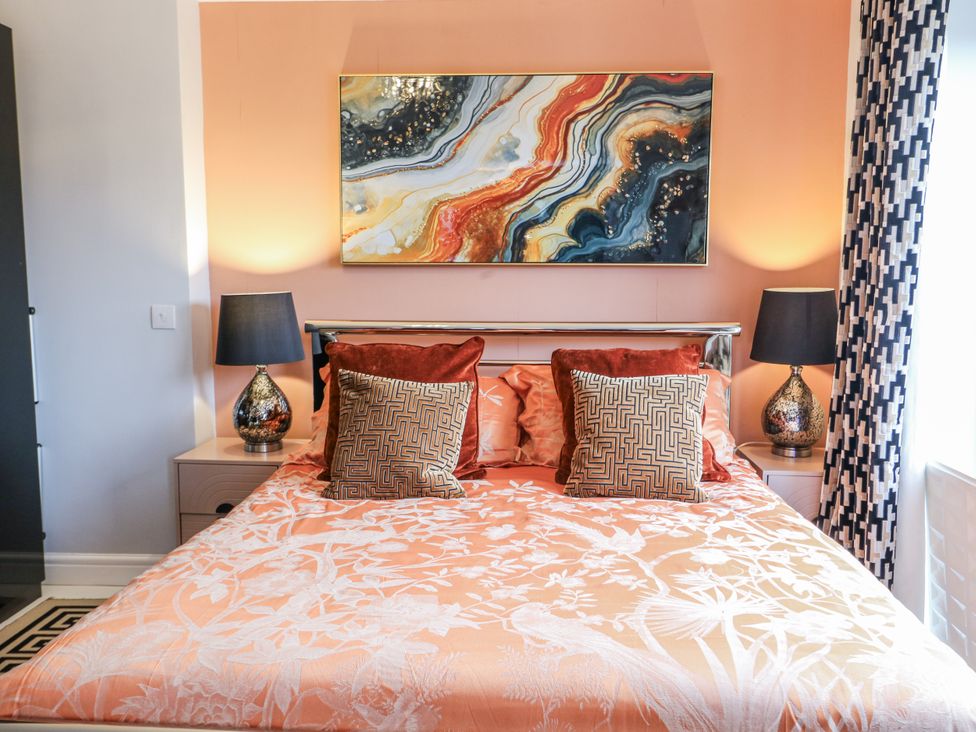 A bedroom featuring a bed with cushions and bedside lamps at Smithy Cottage in Cemaes Bay