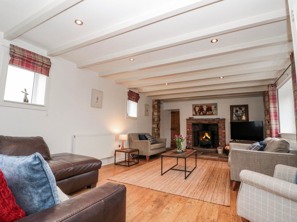 A living room with a fireplace and seating arrangements at Wold Cottage in Hunmanby