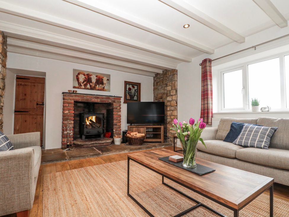 A living room with a fireplace and sofa at Wold Cottage in Hunmanby