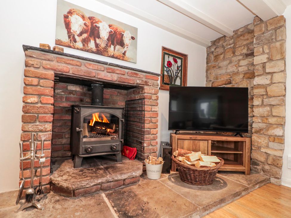 A living room with a fireplace and television at Wold Cottage in Hunmanby