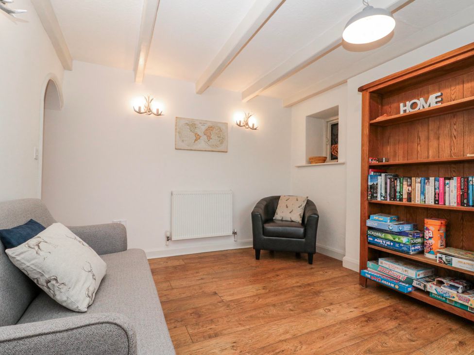 A sitting room with a sofa and bookshelf at Wold Cottage in Hunmanby