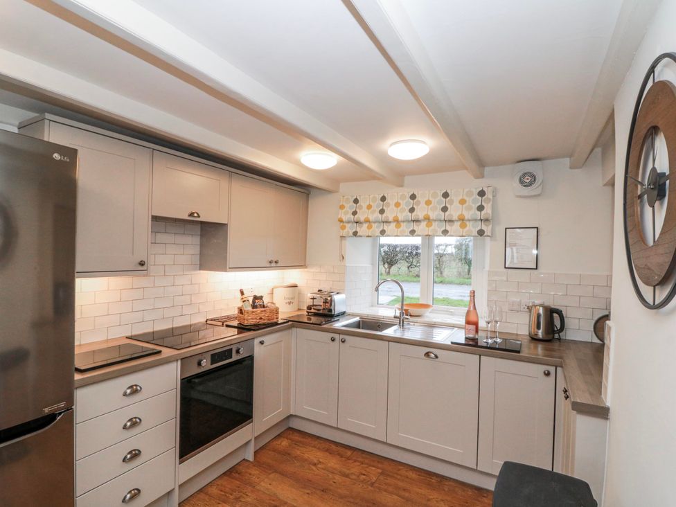 A kitchen equipped with appliances and a window at Wold Cottage in Hunmanby