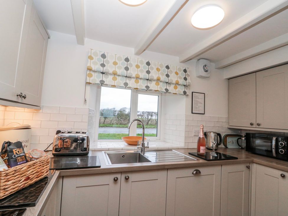 A kitchen with various appliances and a window at Wold Cottage in Hunmanby