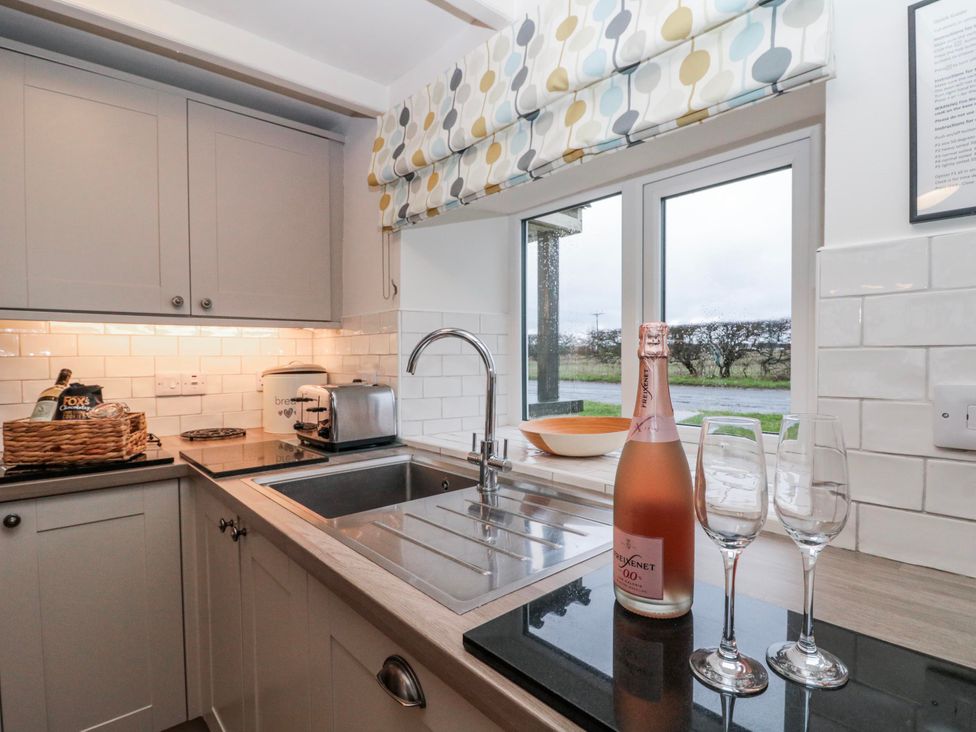 A kitchen with a sink and bottle of champagne at Wold Cottage in Hunmanby