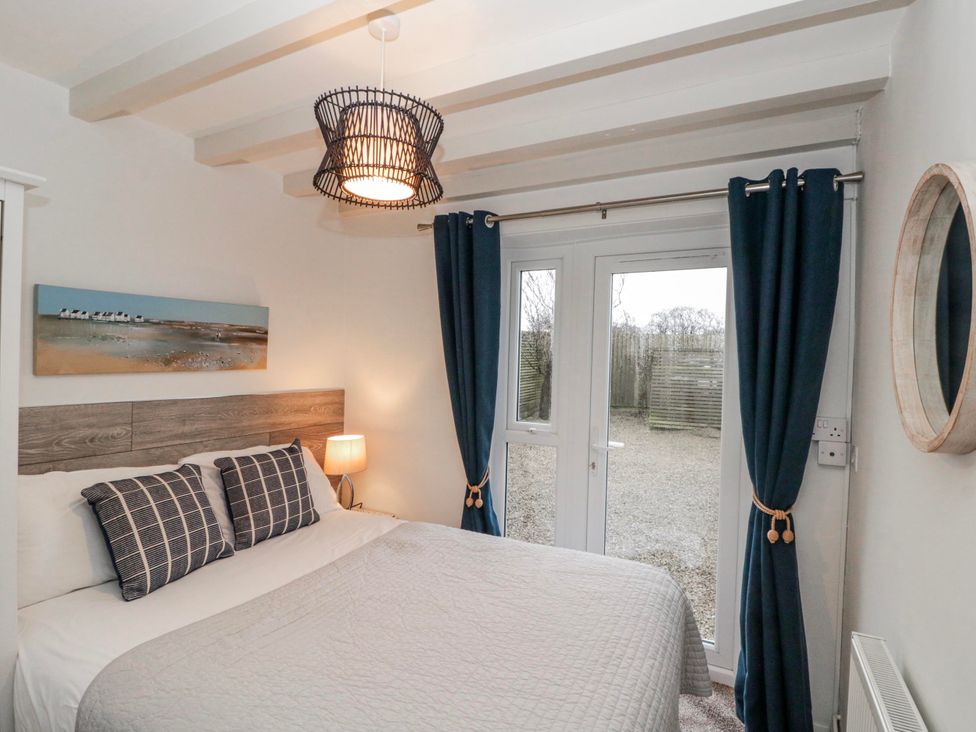 A bedroom with a bed and sliding door at Wold Cottage in Hunmanby