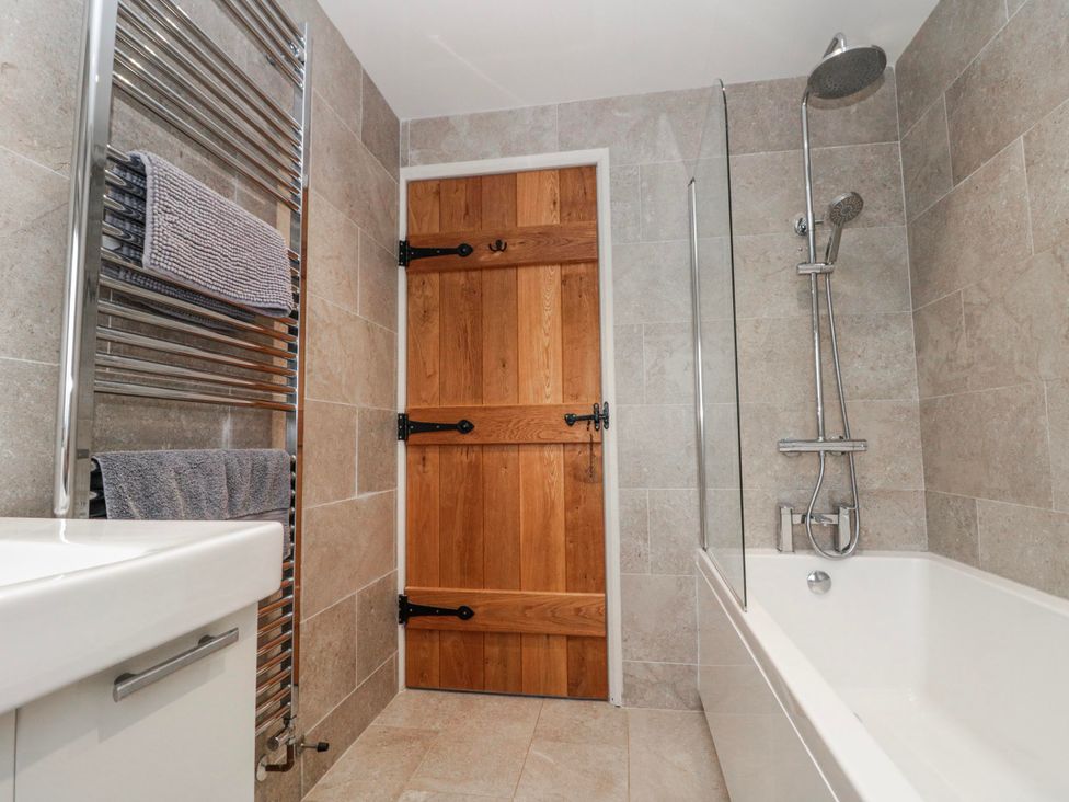 A bathroom with a towel radiator and a wooden door at Wold Cottage in Hunmanby