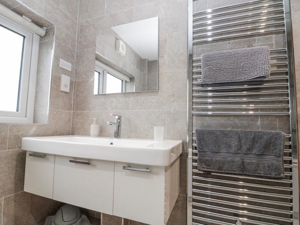 A bathroom with a sink, mirror, and towel radiator at Wold Cottage in Hunmanby