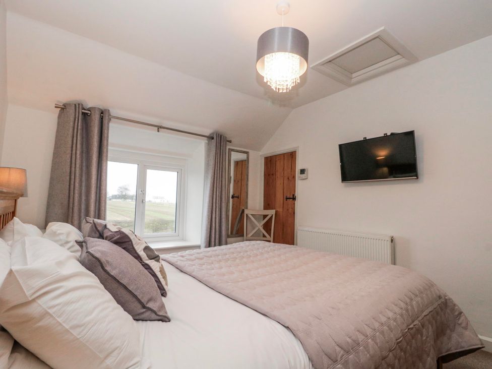 A bedroom with a bed and television at Wold Cottage in Hunmanby