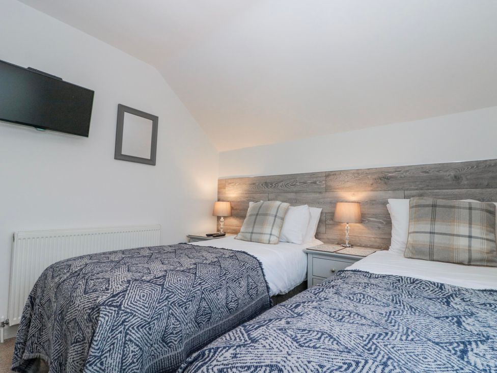 A bedroom with two twin beds and a television at Wold Cottage in Hunmanby