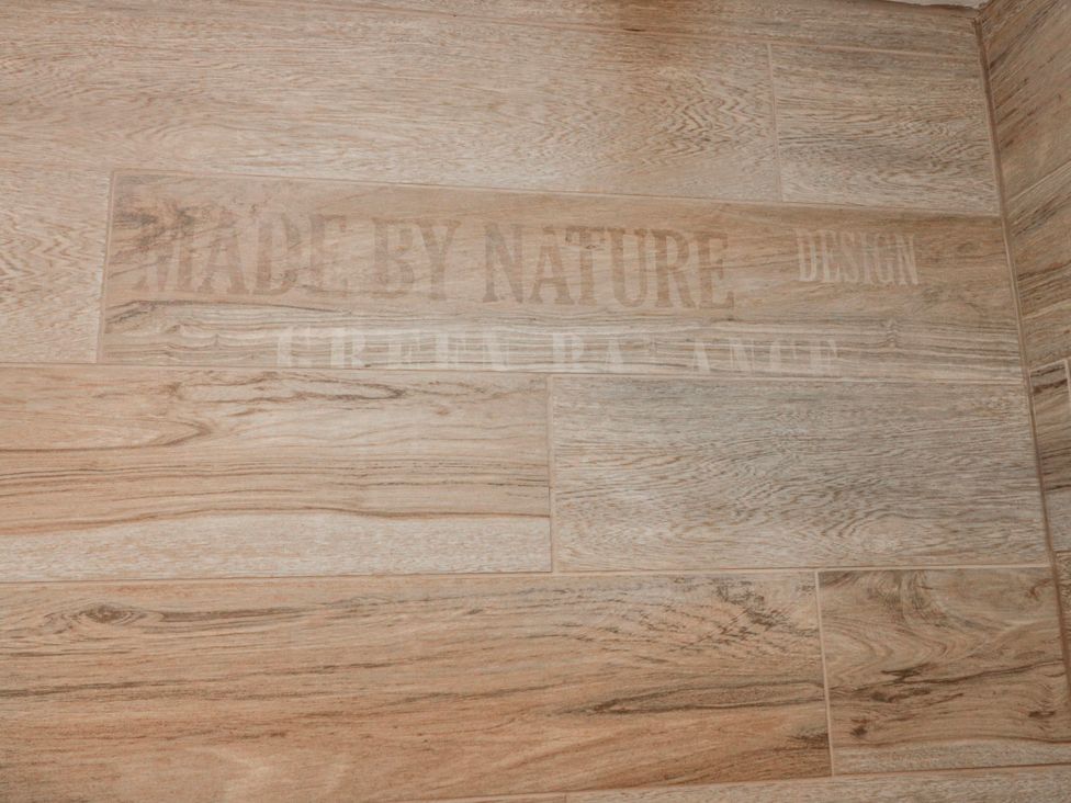 A close-up of wooden-style flooring with text at Wold Cottage in Hunmanby