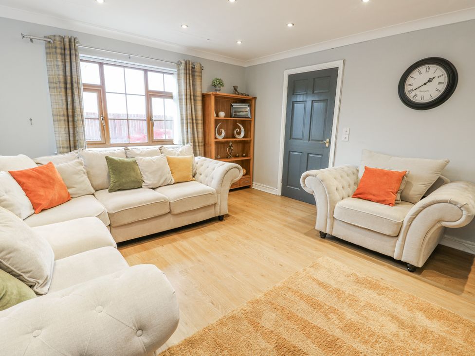 A living room with a sofa and armchair at 1 The Old Smithy in Cemaes Bay