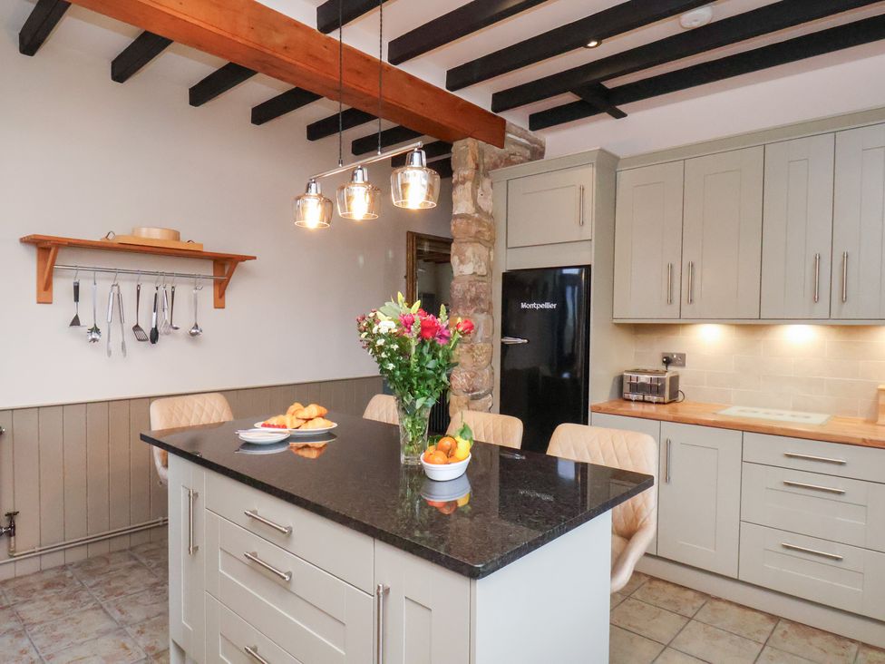 A kitchen with an island and flowers at The Farmhouse in Boggle Hole near Robin Hood's Bay