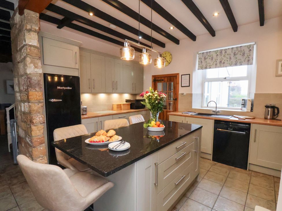 A kitchen with a central island and refrigerator at The Farmhouse in Boggle Hole near Robin Hood's Bay
