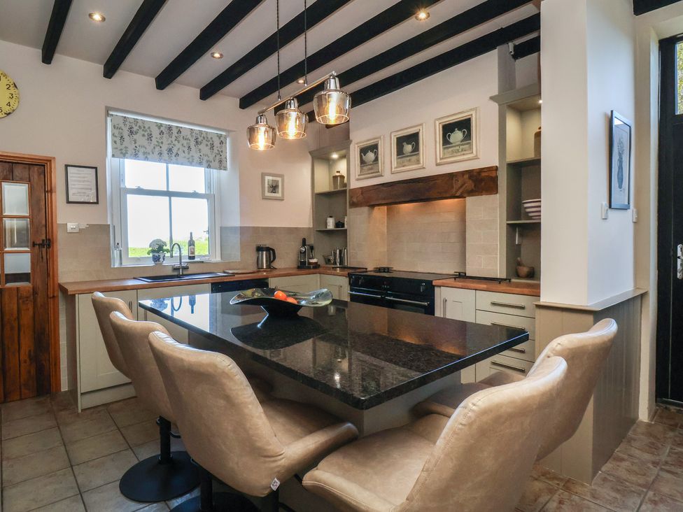 A kitchen with a granite island and bar stools at The Farmhouse in Boggle Hole near Robin Hood's Bay