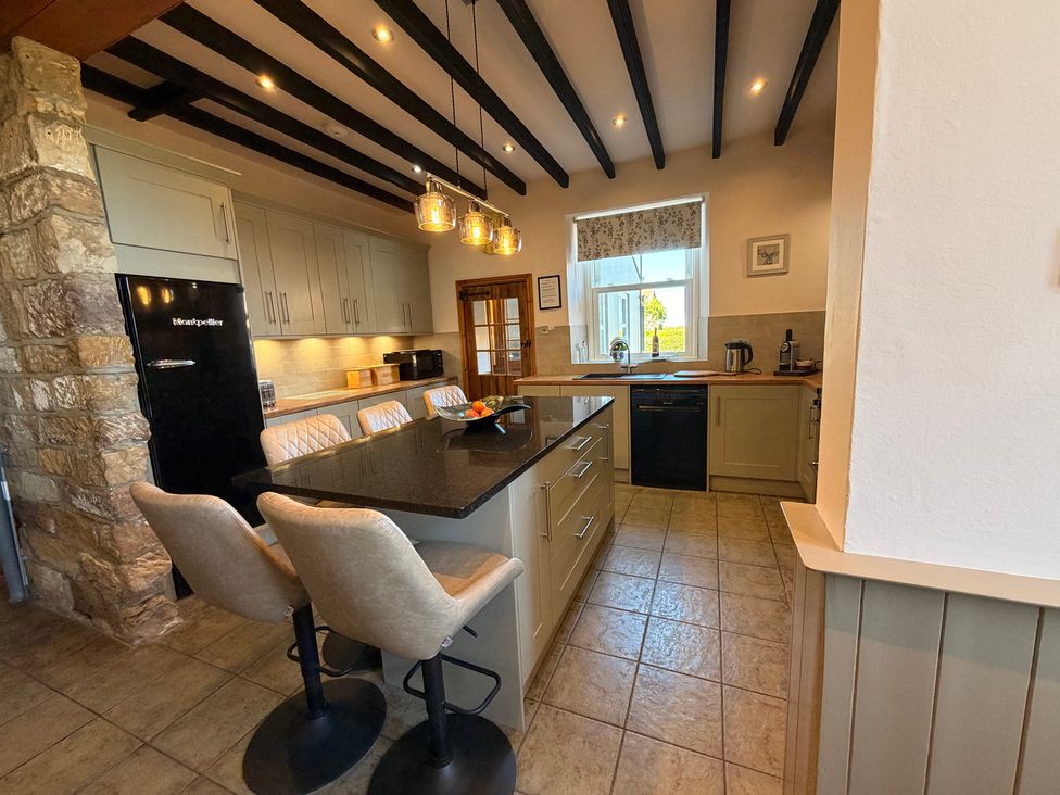 A kitchen with an island and black refrigerator at The Farmhouse in Boggle Hole near Robin Hood's Bay