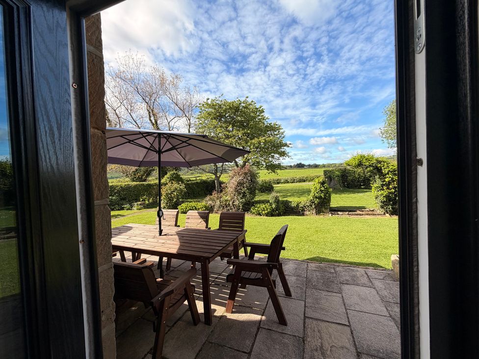 A garden with a table and chairs under an umbrella at The Farmhouse in Boggle Hole near Robin Hood's Bay