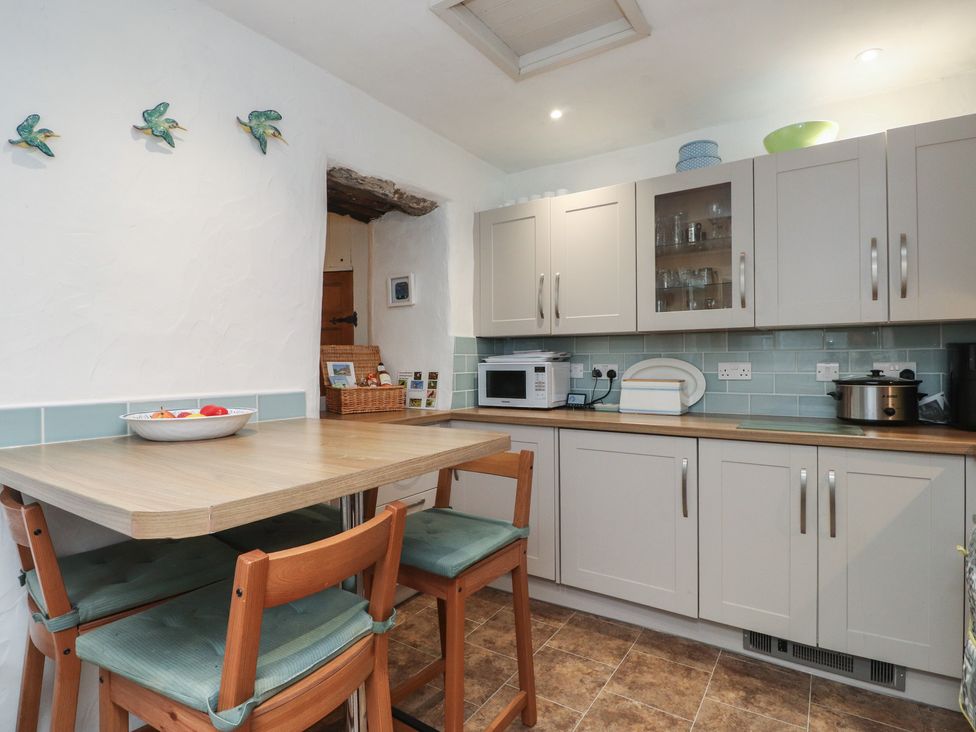 A kitchen with cabinets and a table at Dolfor in Nefyn