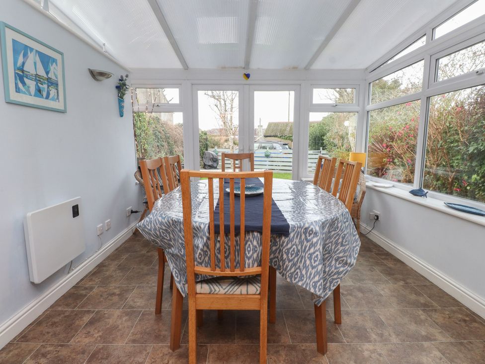 A conservatory with a dining table and chairs at Dolfor in Nefyn