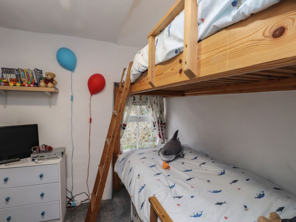 A bedroom with a bunk bed and a television at Dolfor in Nefyn