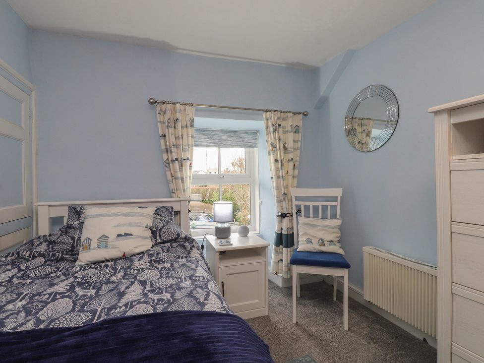 A bedroom with a bed and a chair at Dolfor in Nefyn