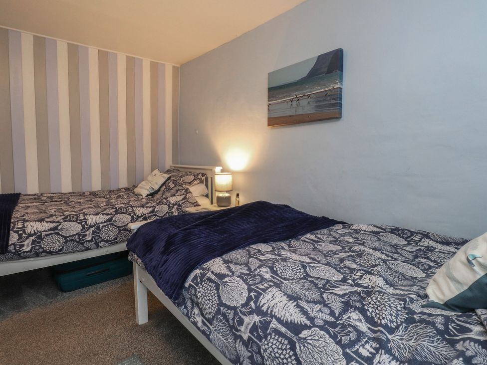 A bedroom with two beds and a lamp at Dolfor Nefyn
