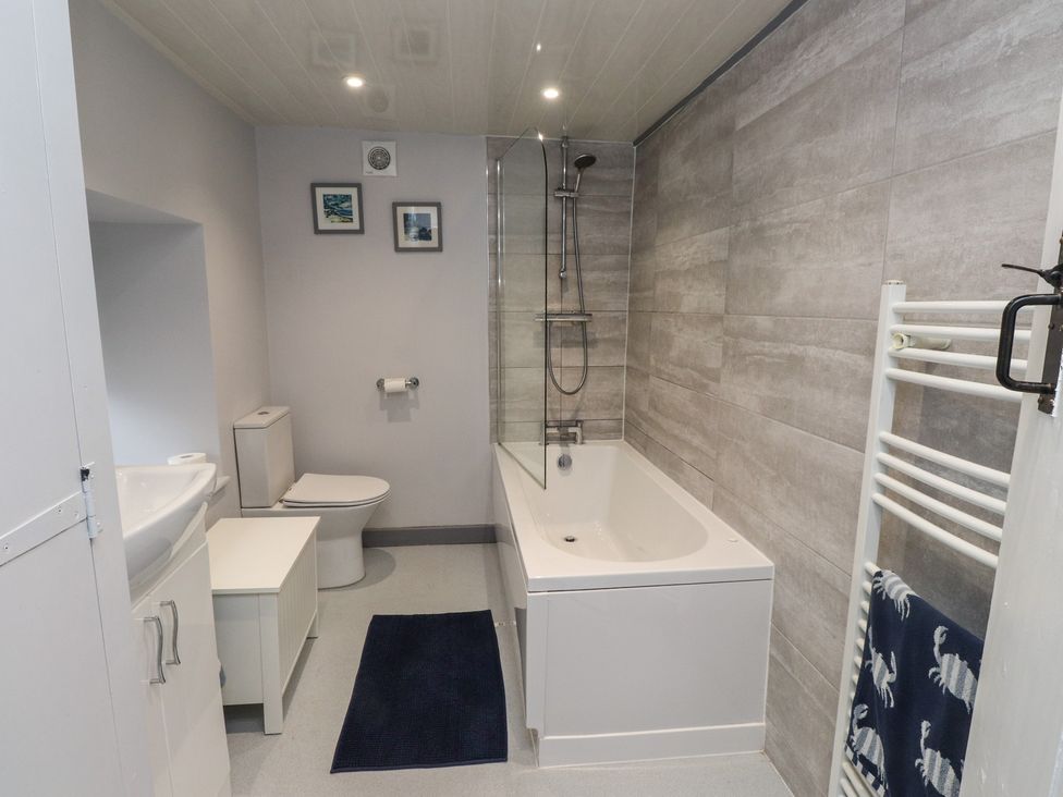 A bathroom with a bathtub, toilet, and sink at Dolfor in Nefyn